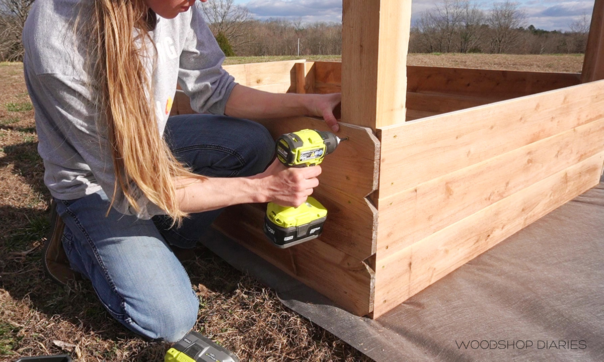 Shara screwing fence picket boards to assemble garden bed boxes