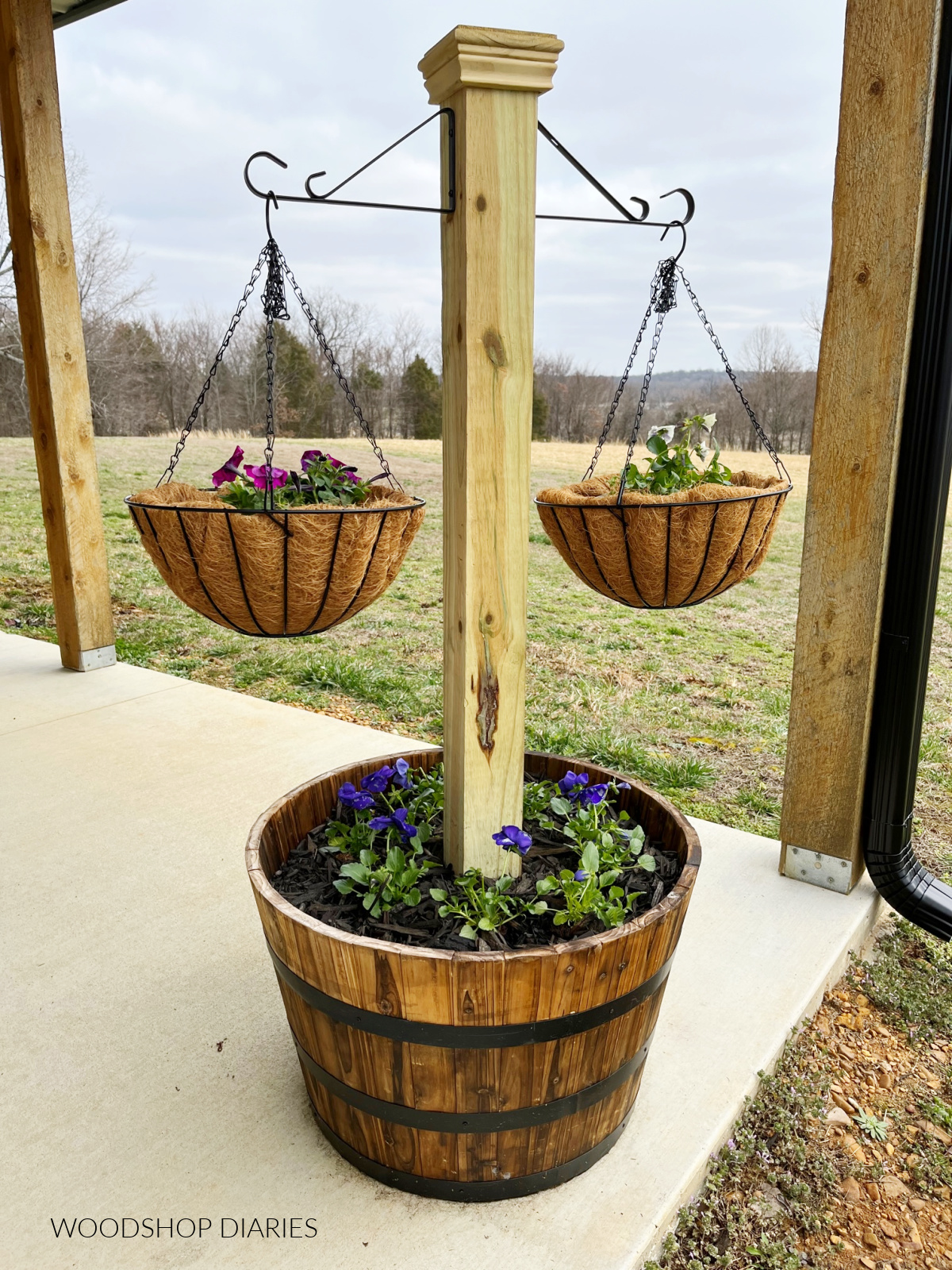 Barrel planter with post and hanging baskets with flowers