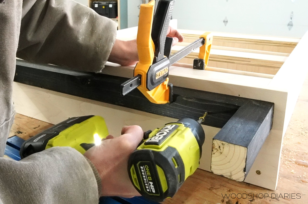 Shara Woodshop Diaries using driver to secure base to bottom of shelf cabinet