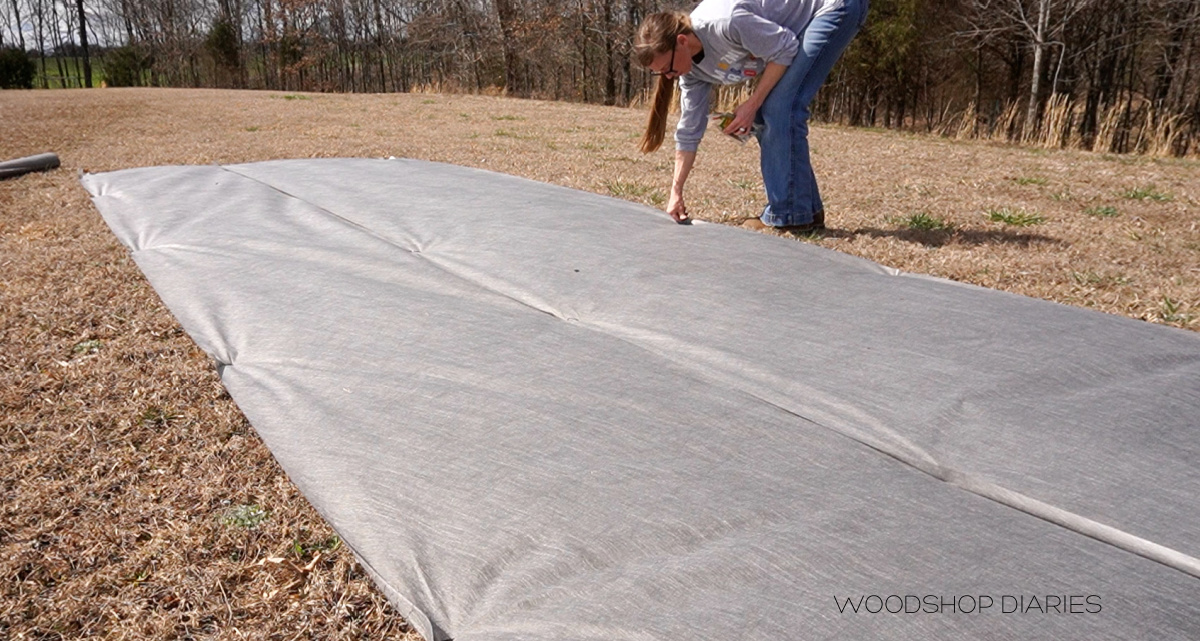 Shara stapling landscape fabric over grass where garden will go