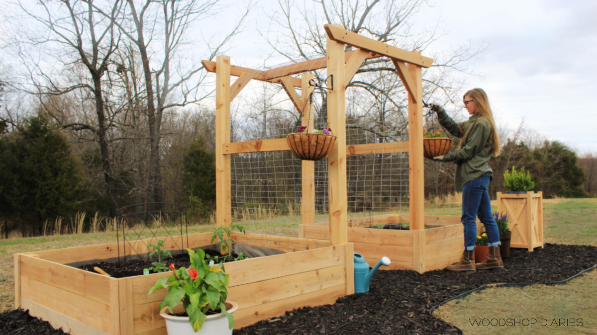 Shara Woodshop Diaries hanging planter baskets with flowers on garden arbor