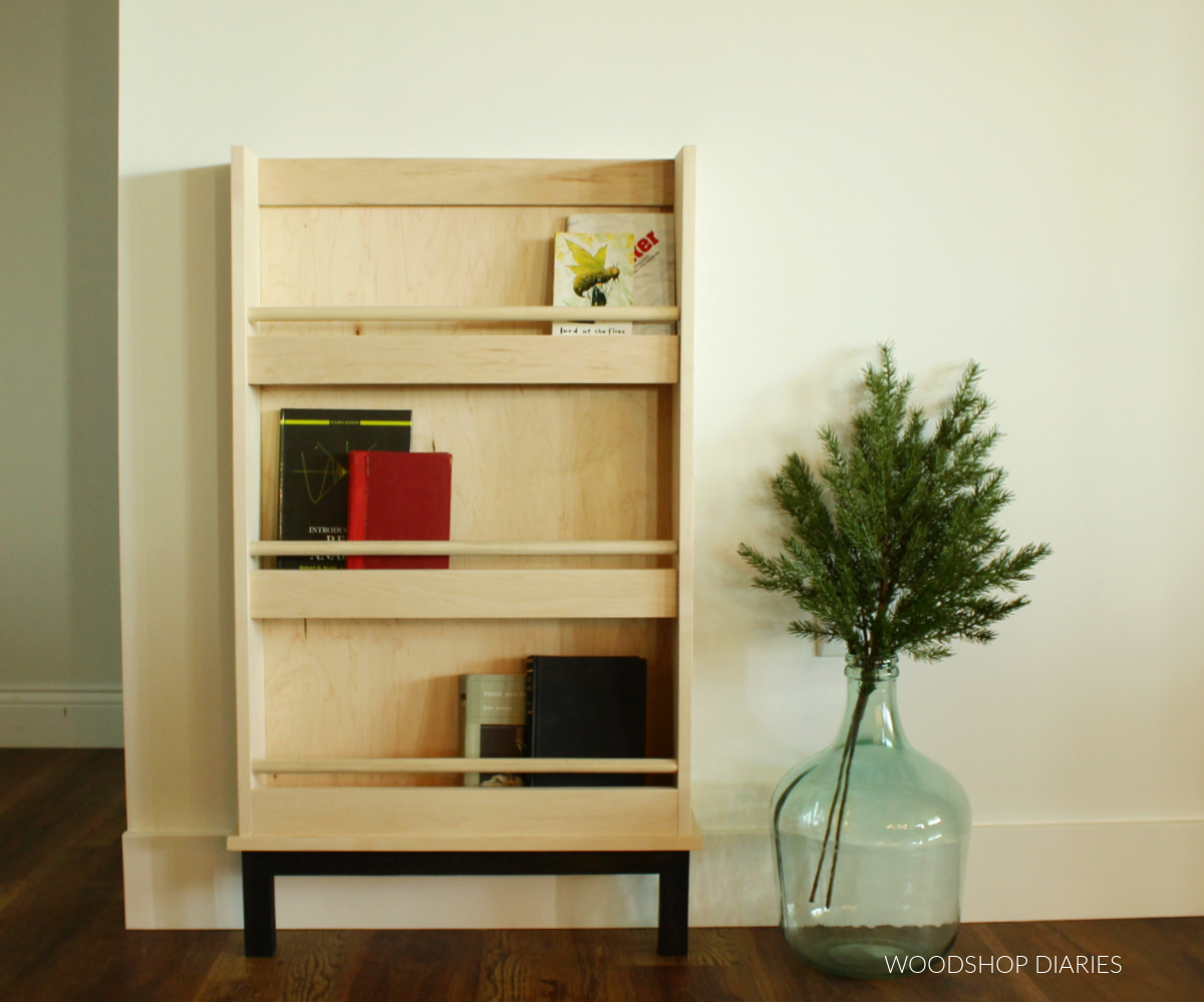 natural plywood book rack shelf with books inside leaning against wall