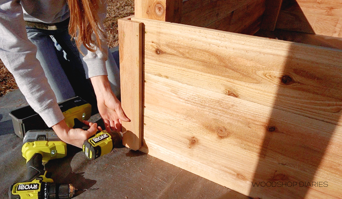 Shara installing corner trim on garden beds using screws