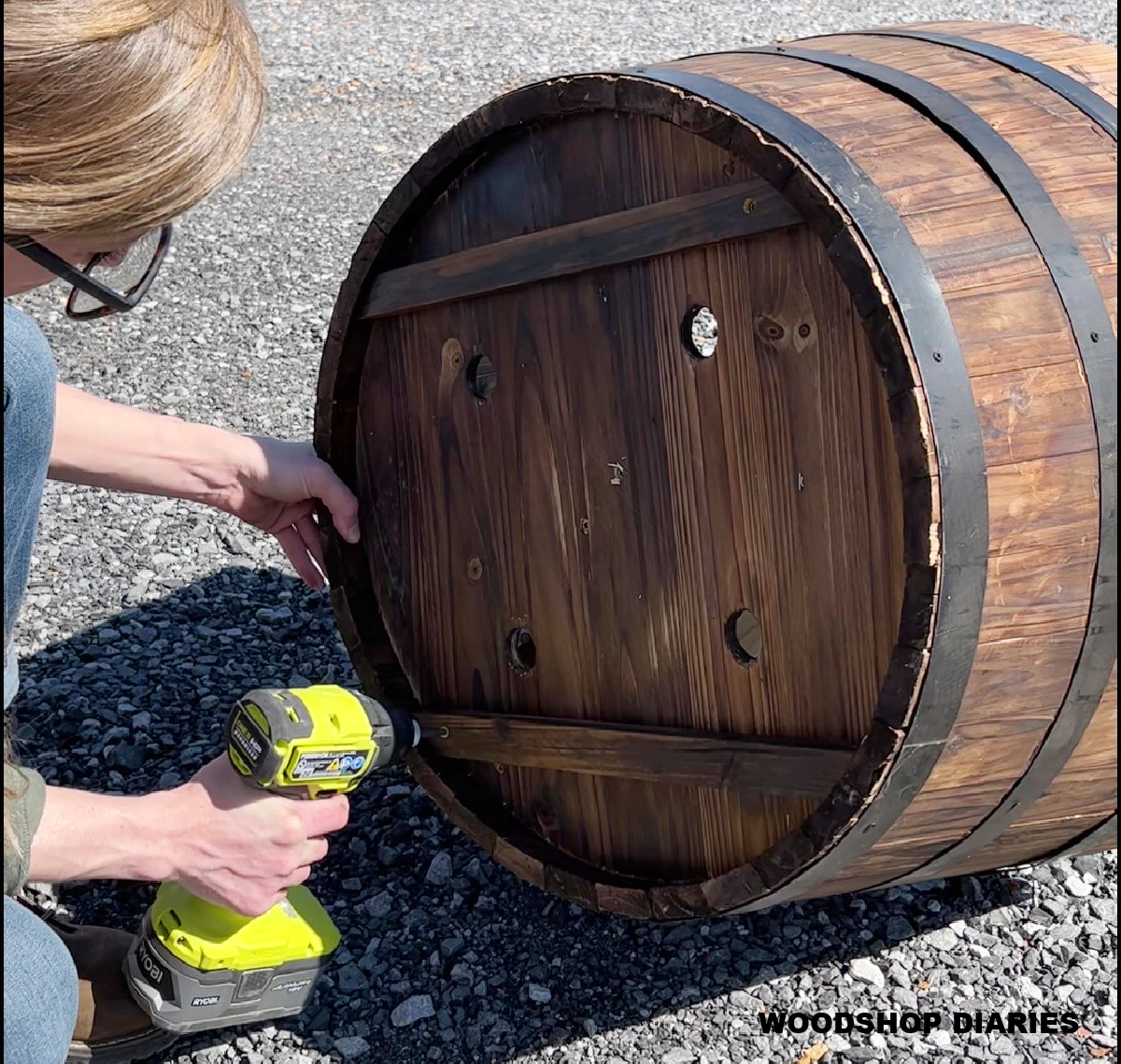 Barrel planter flipped on side--Shara Woodshop Diaries screwing supports to bottom of barrel