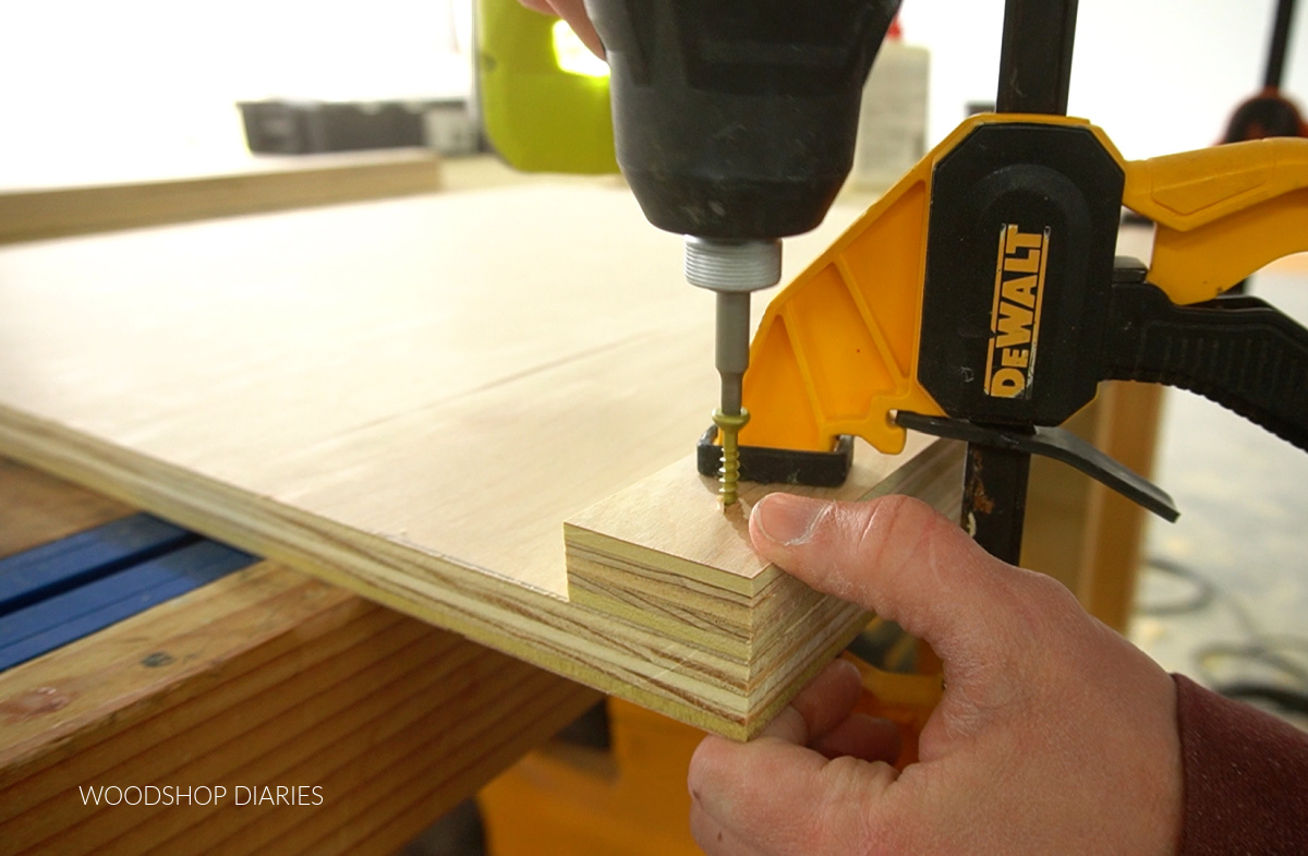 Screwing scrap plywood piece onto bottom front edge of shelf