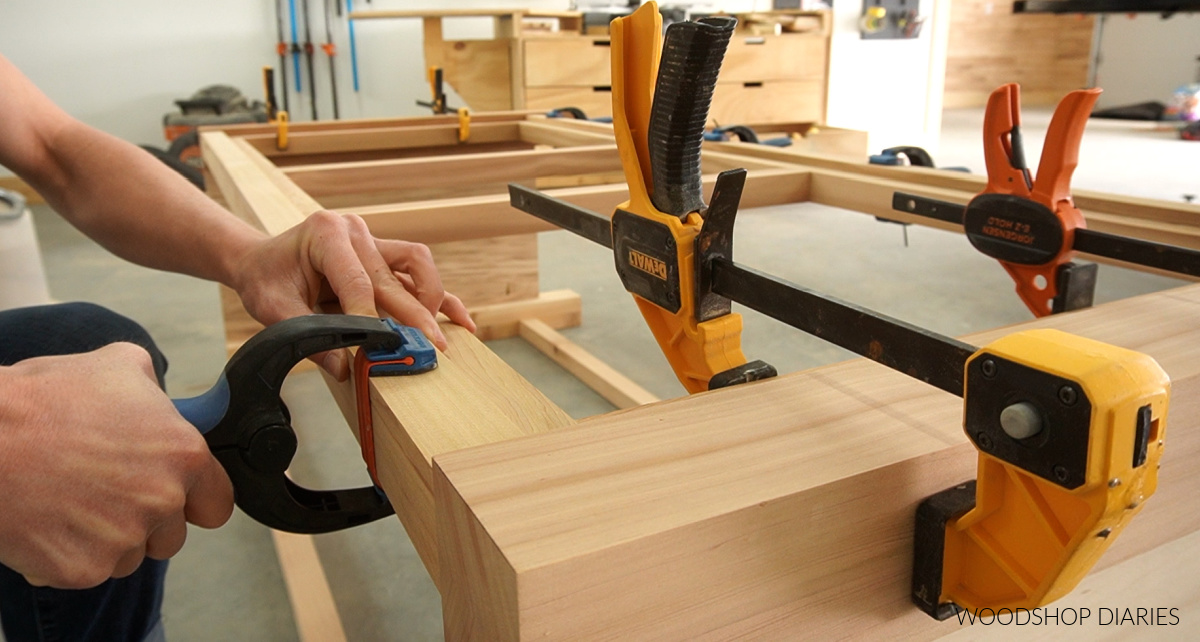 Placing a clamp on trim piece at top of bathroom vanity frame