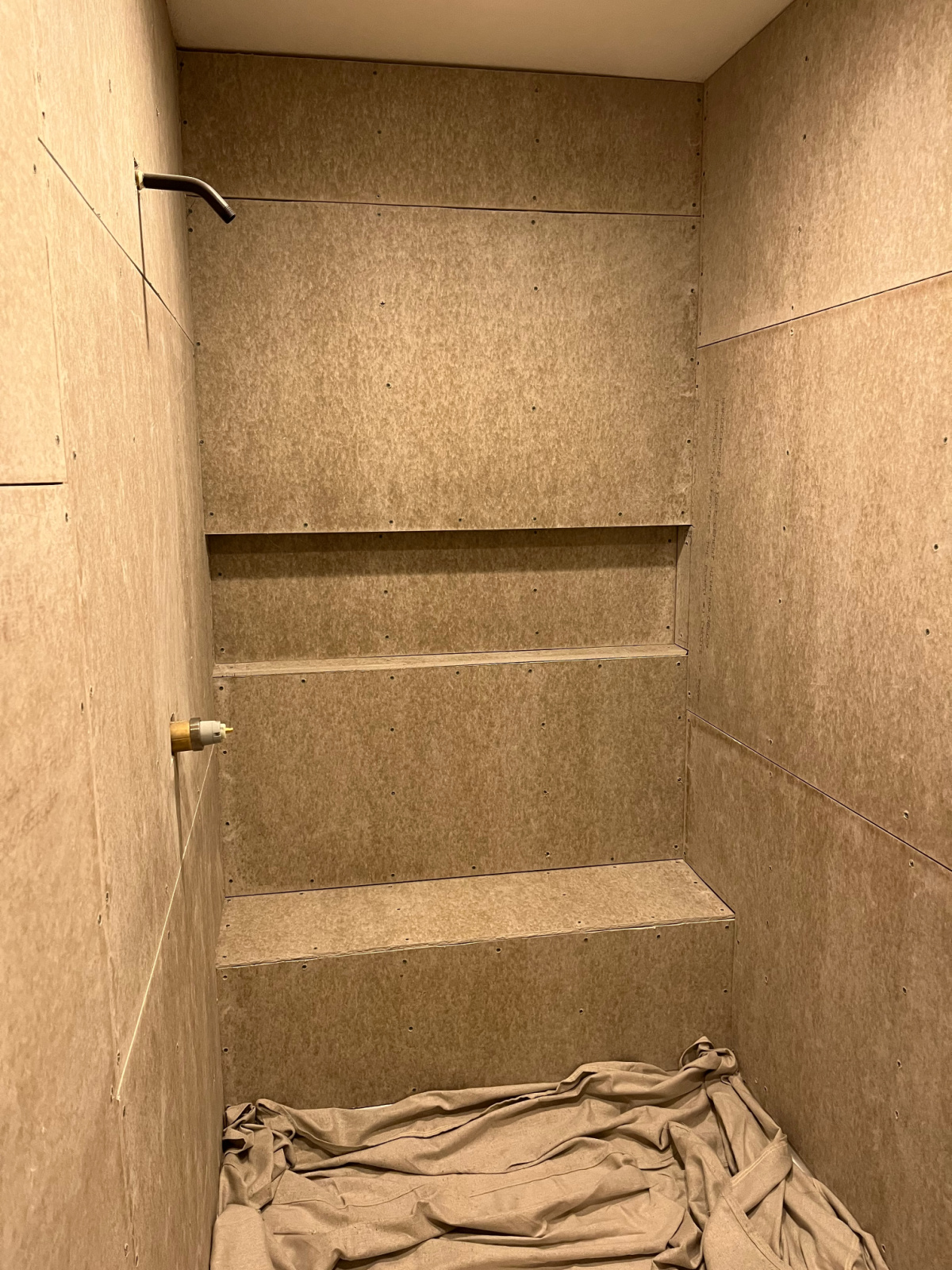 Cement board installed in shower on walls, shelf, and bench seat