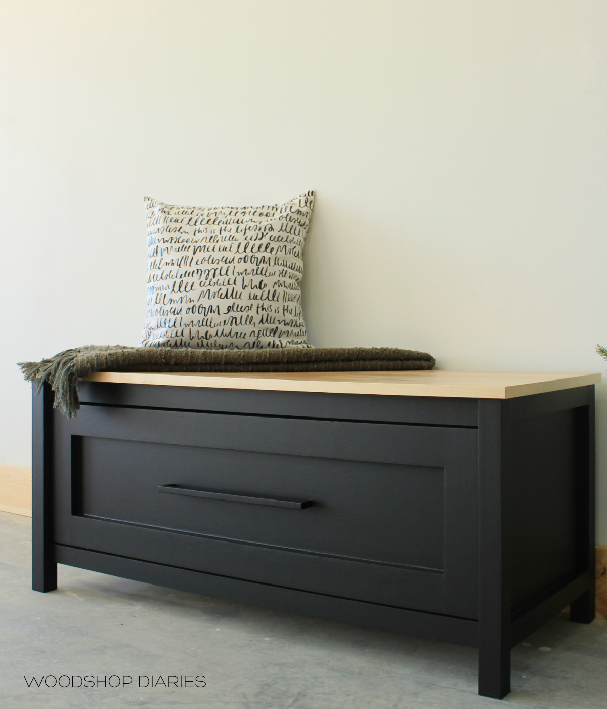 Black and wood DIY storage bench with large drawer against white wall