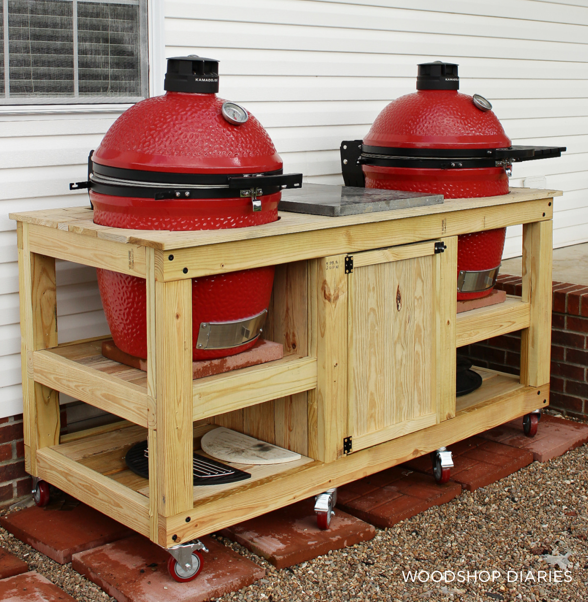 Mobile wooden grill cart with two ceramic Kamado Joe Grills on open shelves with accessories stored below