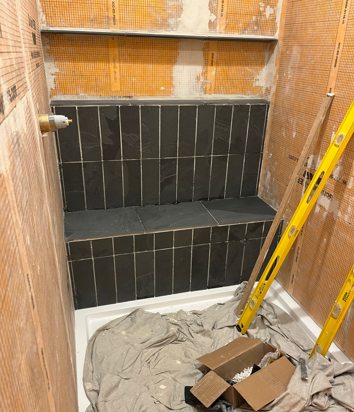 Back wall of shower partially tiled with dark slate