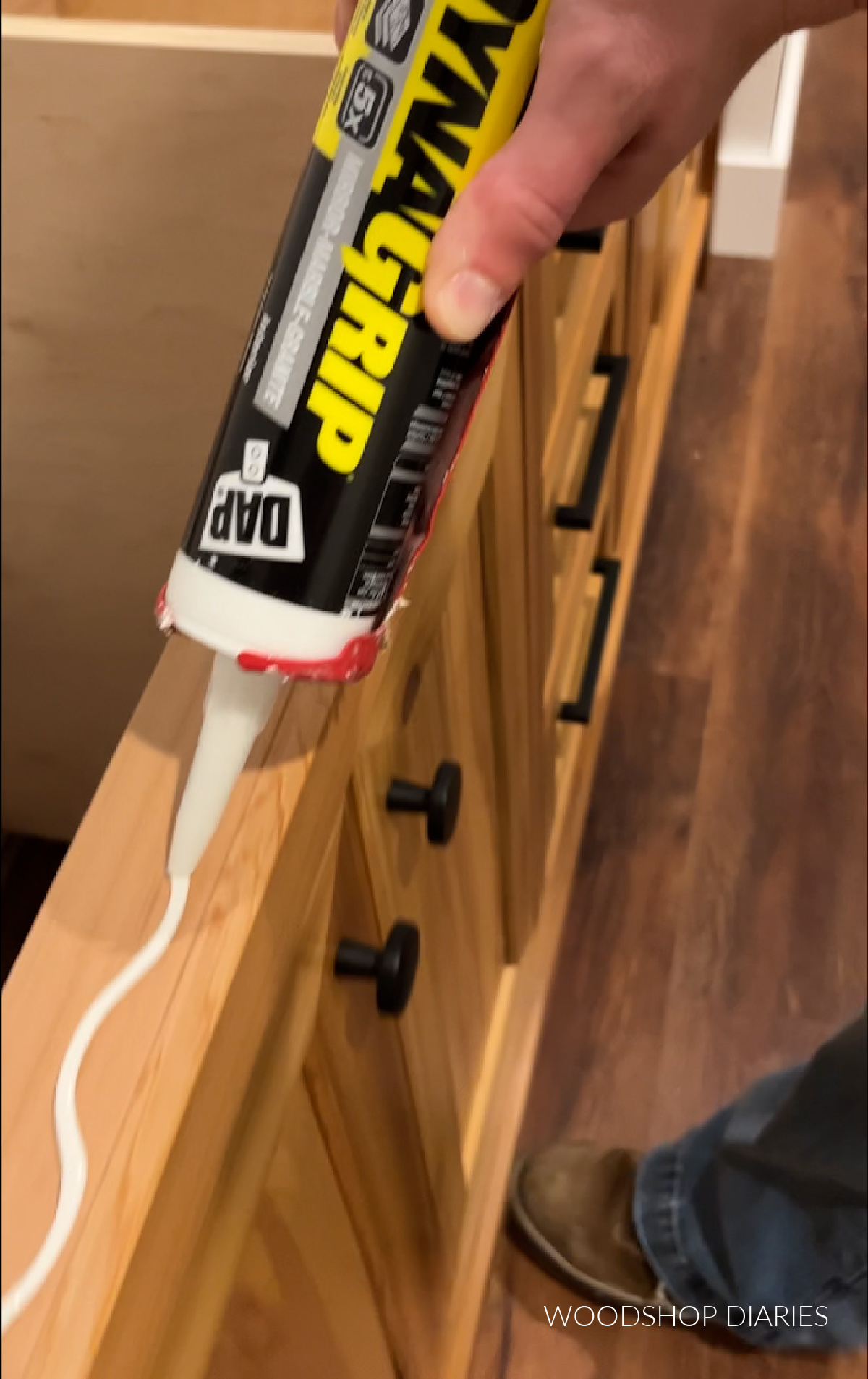 Close up applying DynaGrip to top of wooden vanity