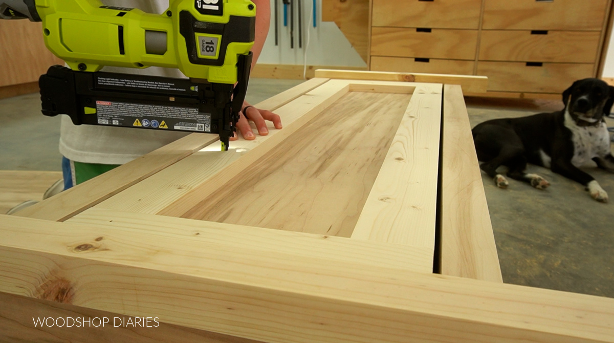 Using nail gun to secure drawer front pieces on drawer of storage bench