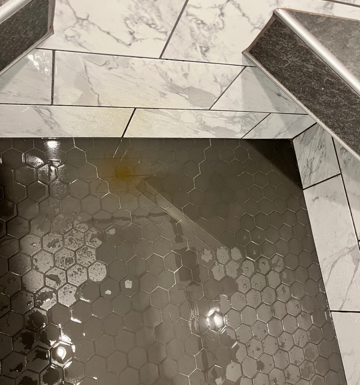 Water pooling on shower tiles on floor