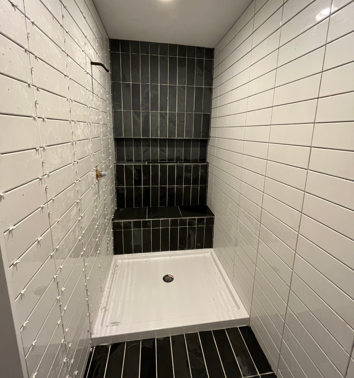 Dark slate and white subway tile shower before grout is applied