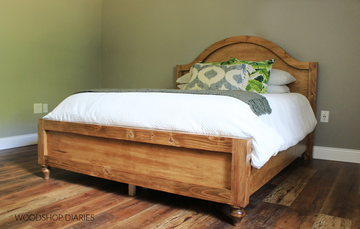 Wooden bed frame with arched headboard and decorative furniture feet with white comforter