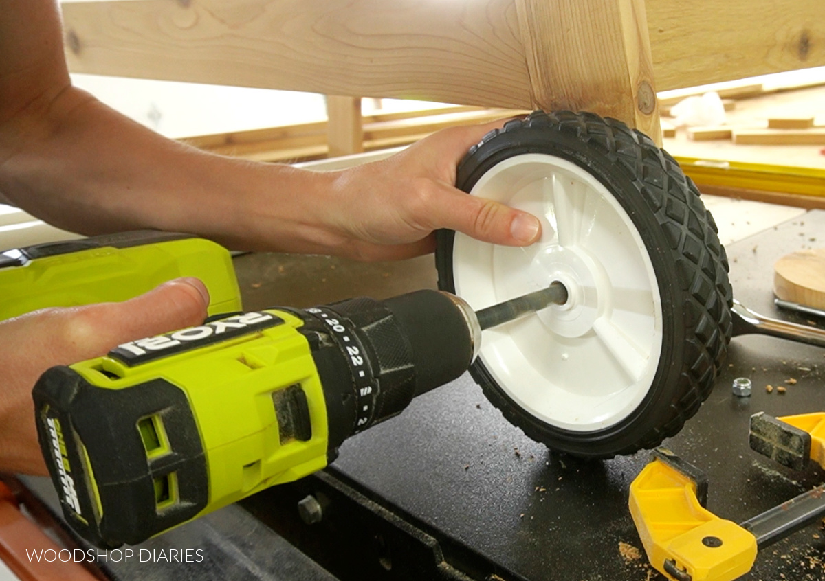 Close up of drilling out center hole of plastic wheel on potting bench leg