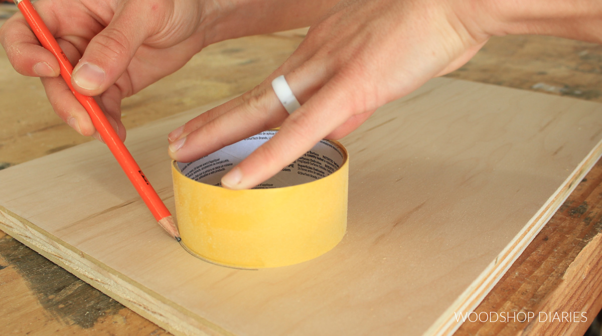 Tracing around outside of roll of tape onto plywood surface