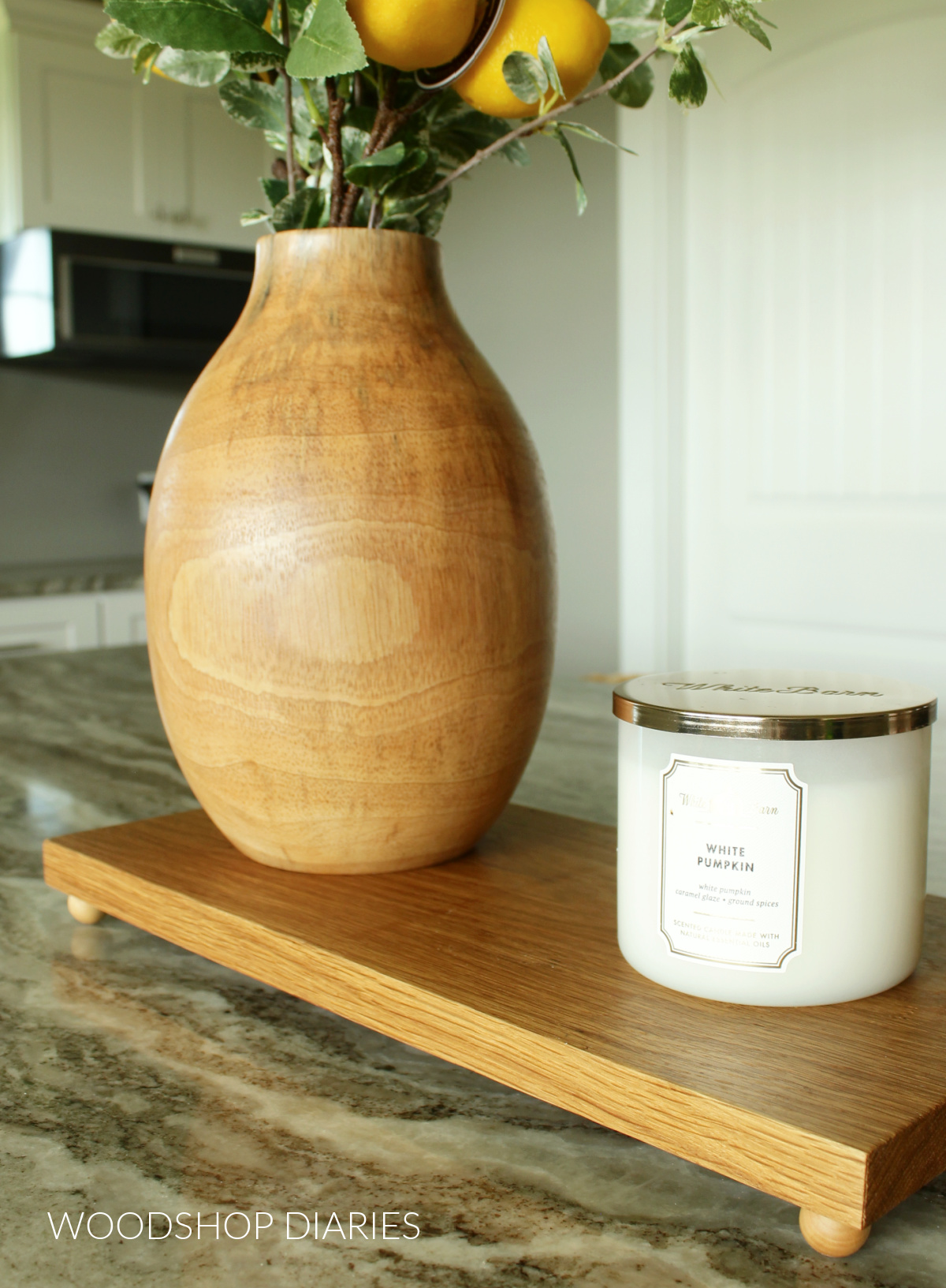 Larger wooden tray with wood ball feet used as centerpiece on kitchen island