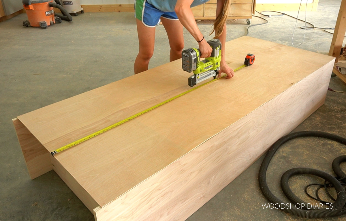 Using a stapler to secure the back panel to the bookshelf carcass