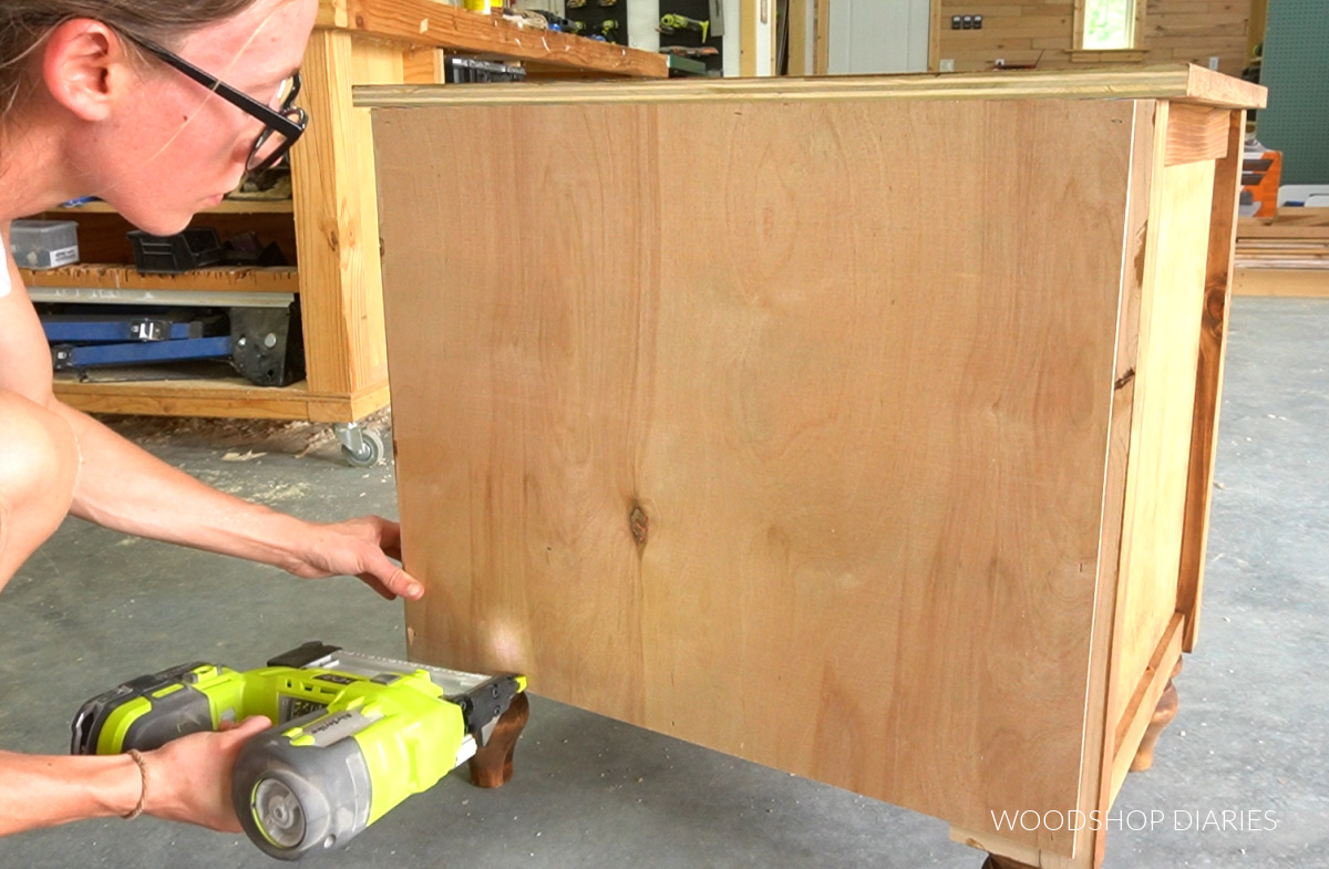 Shara Woodshop Diaries stapling back panel onto stained nightstand body