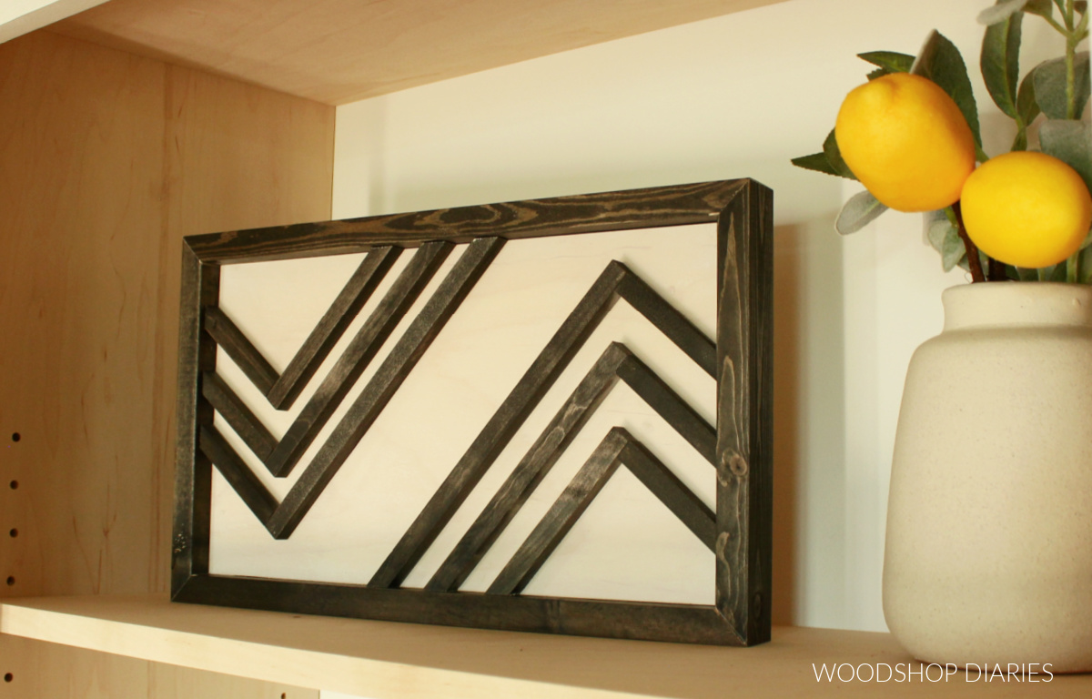 Black and white scrap wood modern geometric wooden art piece in shelf next to vase