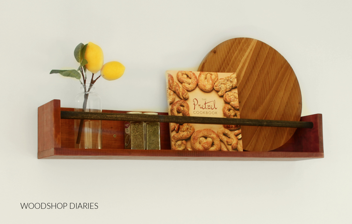 Wood Wall shelf with black dowel rod used as spice and book rack