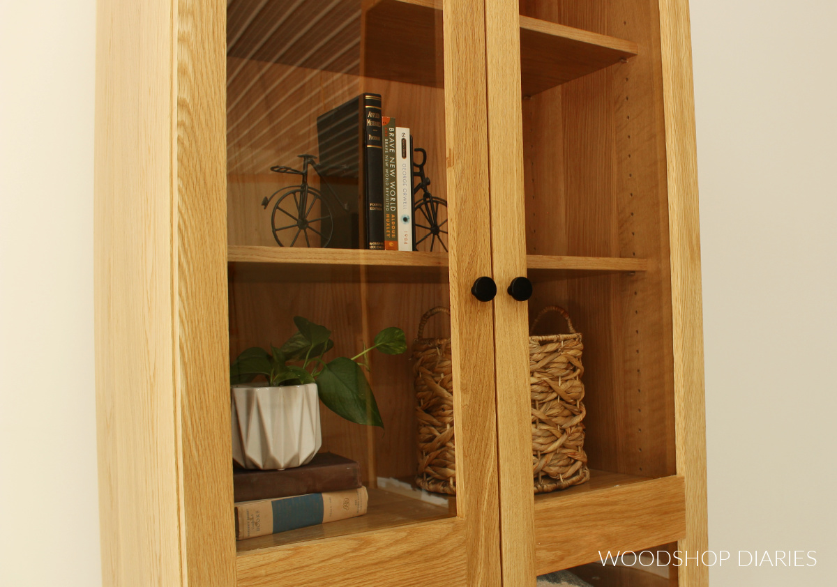 Close up of front of display cabinet looking through plexiglass panels at books and baskets inside