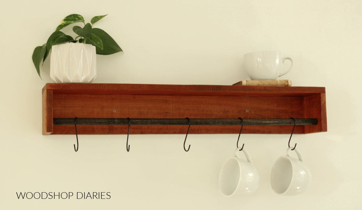 Wood wall shelf with black dowel rod hanging coffee mugs from S hooks