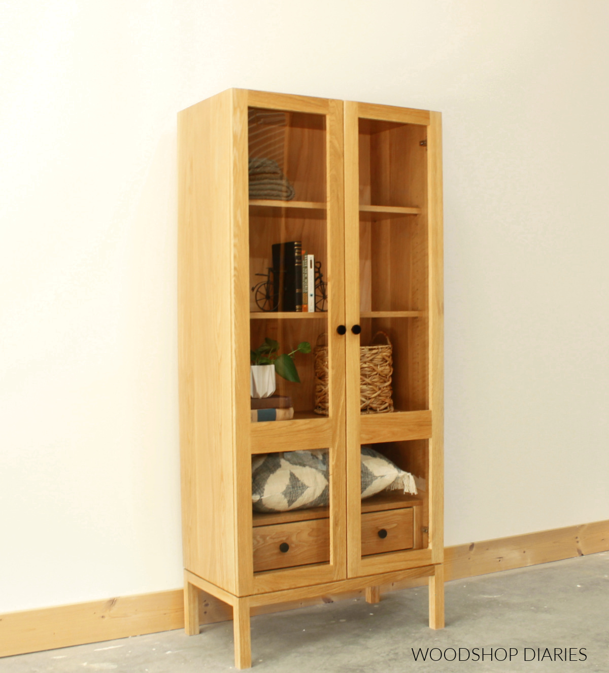 White oak cabinet with glass doors and adjustable shelves with drawer on bottom behind doors