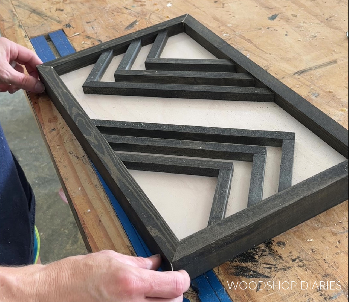 Placing 1x2s around DIY geometric wooden art piece to frame it