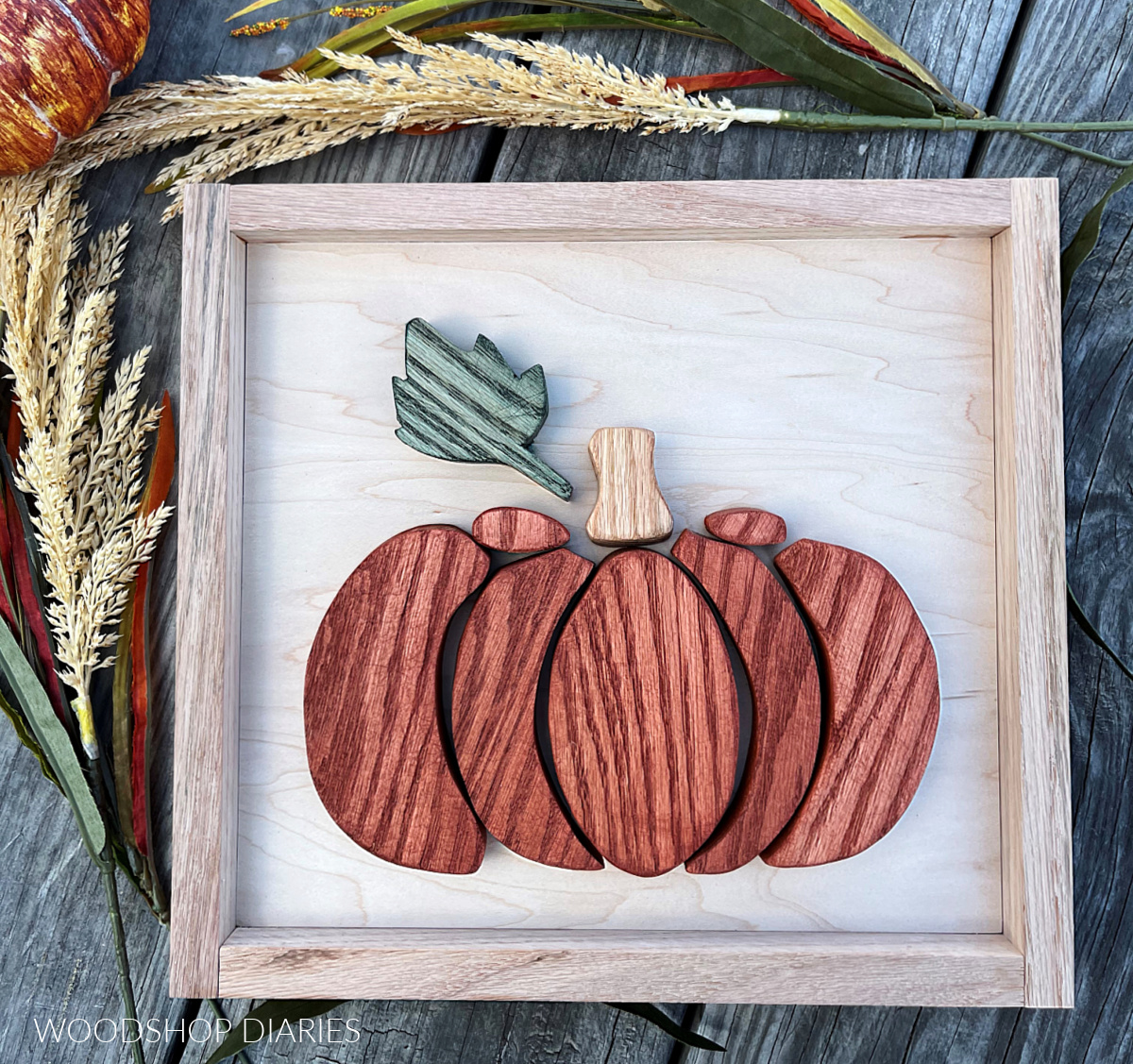 DIY Scrap Wood fall Pumpkin cut out sign on weathered wood back drop with fall foliage around