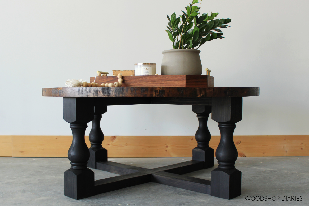 Black and wood round coffee table with decorative legs and X braces between