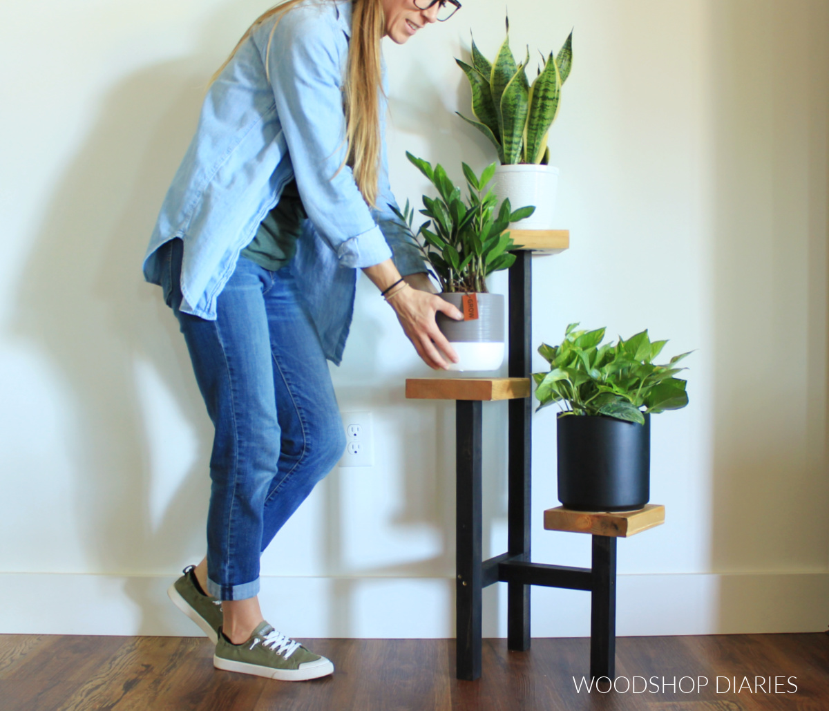 Shara Woodshop Diaries setting plant on tiered black and wood plant stand