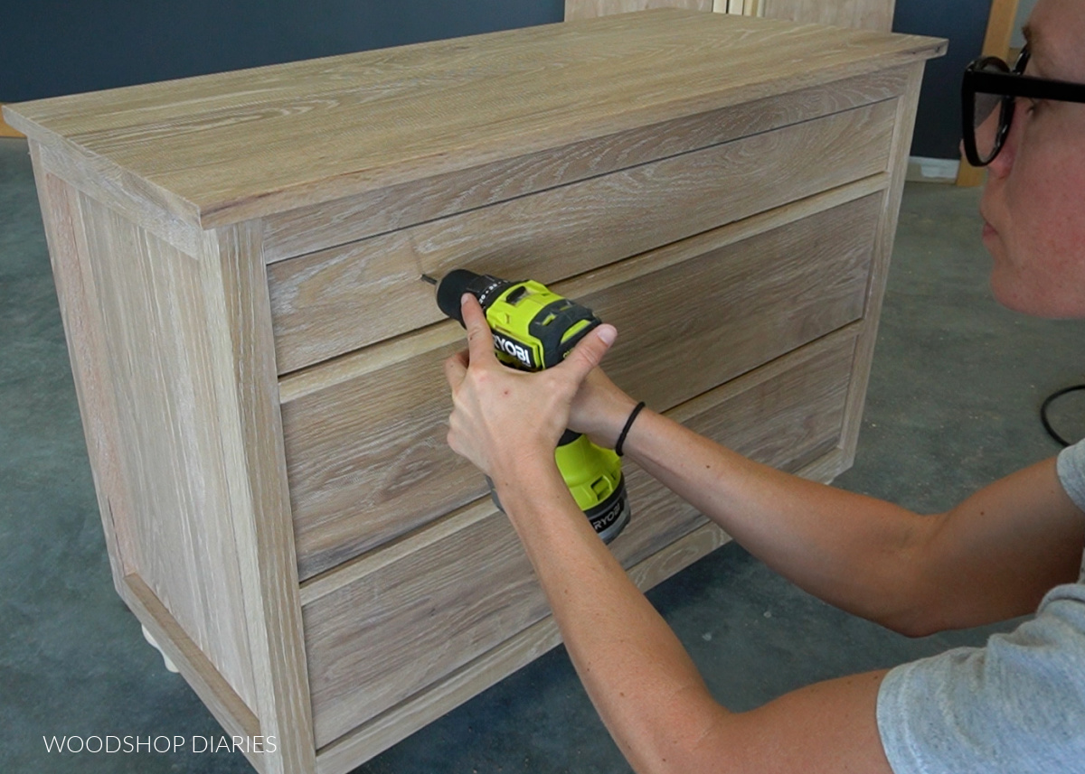 Shara Woodshop Diaries drilling holes to install knobs into dresser drawers