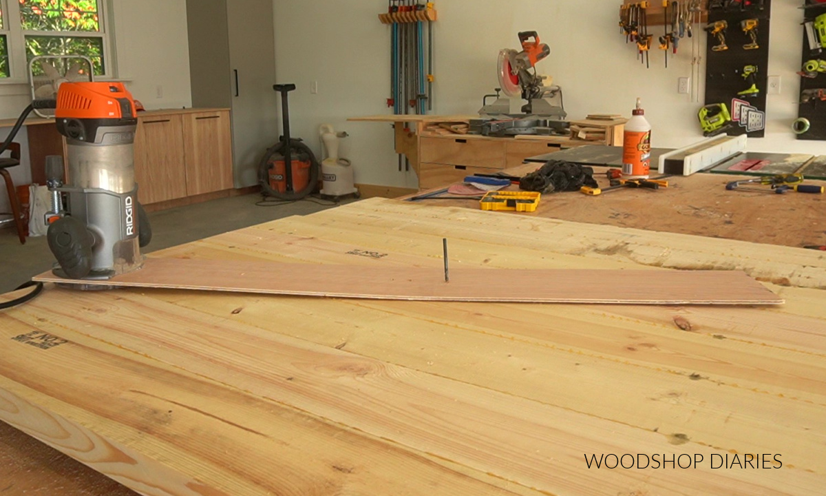 Router set up on circle jig on table top ready to cut with drill bit through pivot point