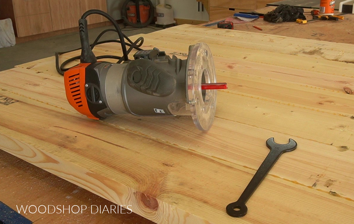 straight bit installed in fixed base router on wooden table top sitting on workbench