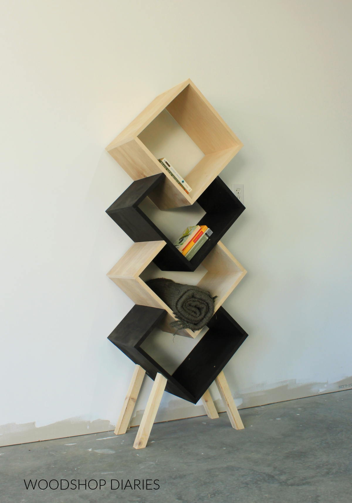 Geometric plywood bookshelf natural wood and black against white wall