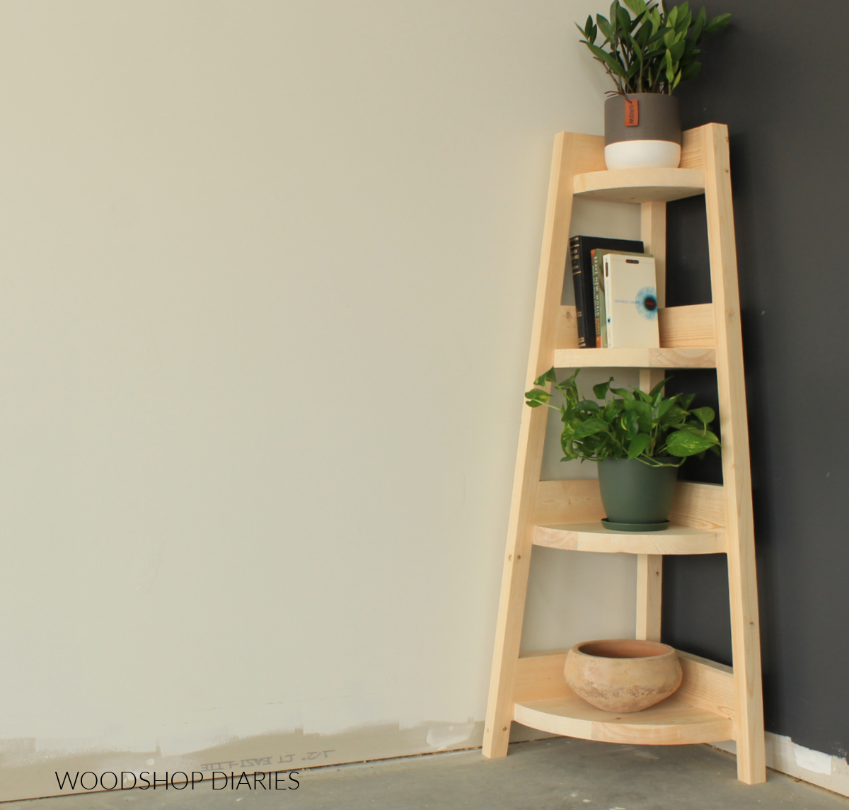 Wooden corner shelf in corner against a black and white wall with books and plants on shelves