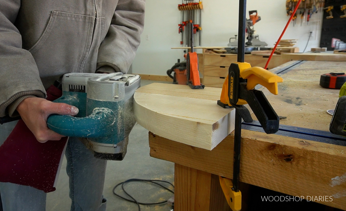 Using a belt sander to smooth rounded edges of corner shelves