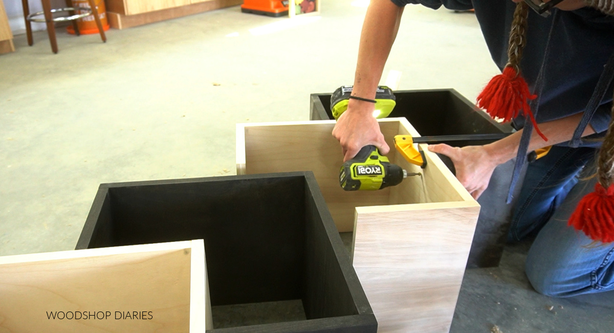 Shara Woodshop Diaries assembling bookshelf boxes together on workshop floor