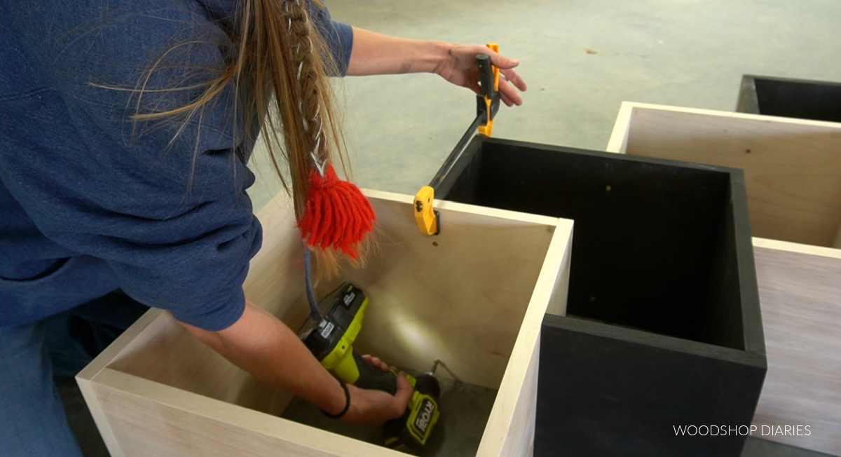 Shara Woodshop Diaries securing bookshelf boxes together on workshop floor