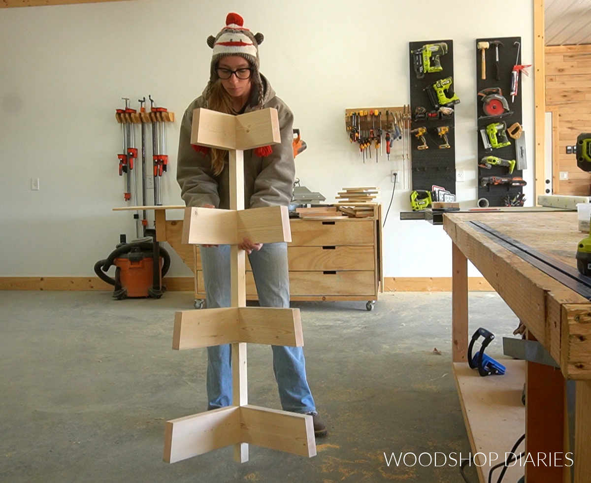 Shara Woodshop Diaries holding corner shelf back post with shelf slats attached onto adjacent ends