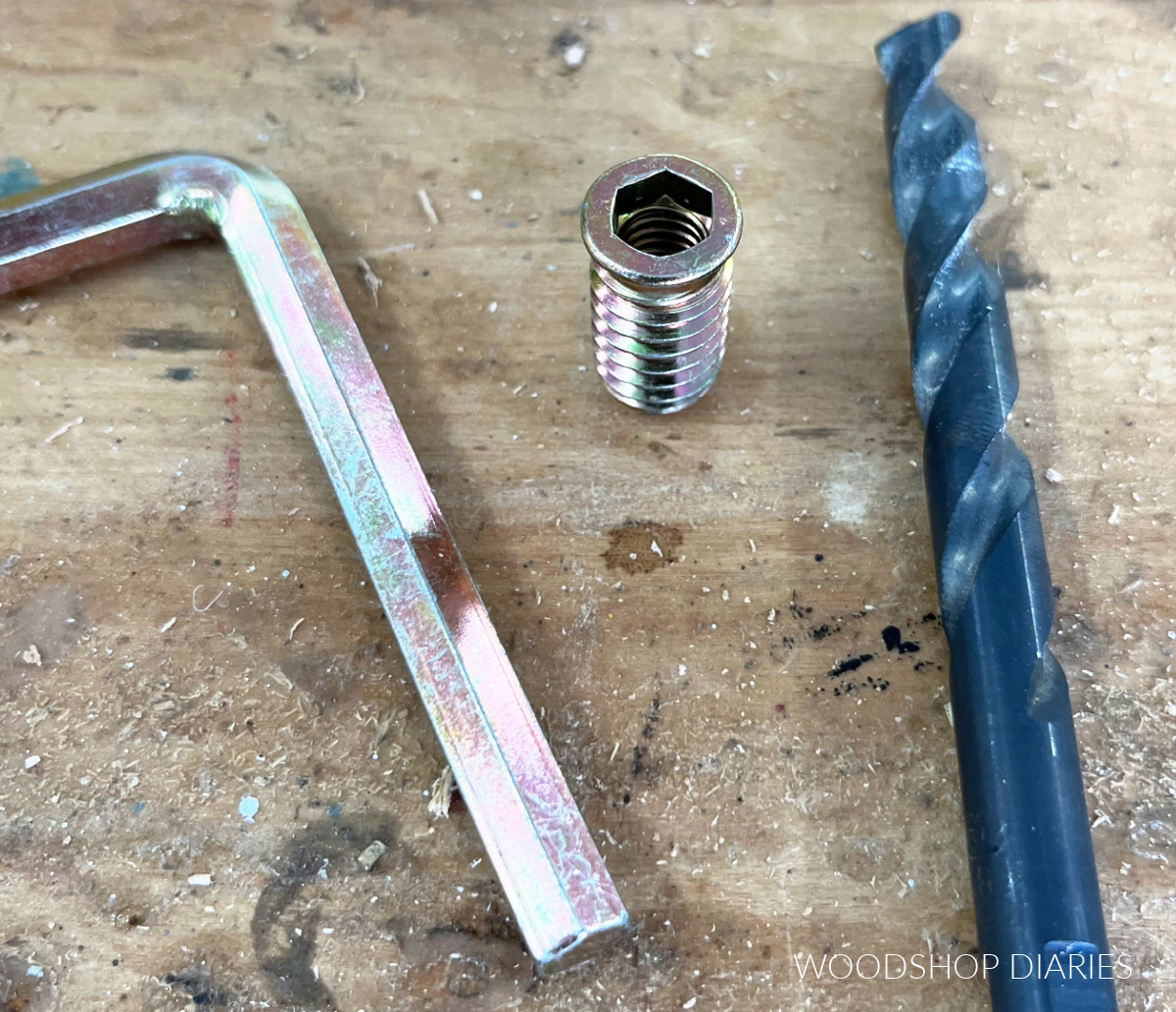 Close up of threaded insert with hex wrench and drill bit on workbench