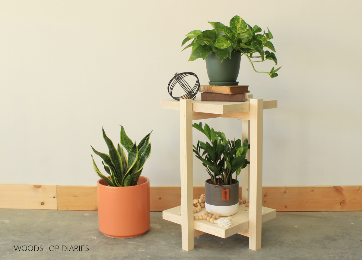 DIY plant stand end table displayed with plants on each shelf and a large plant sitting on floor next to it