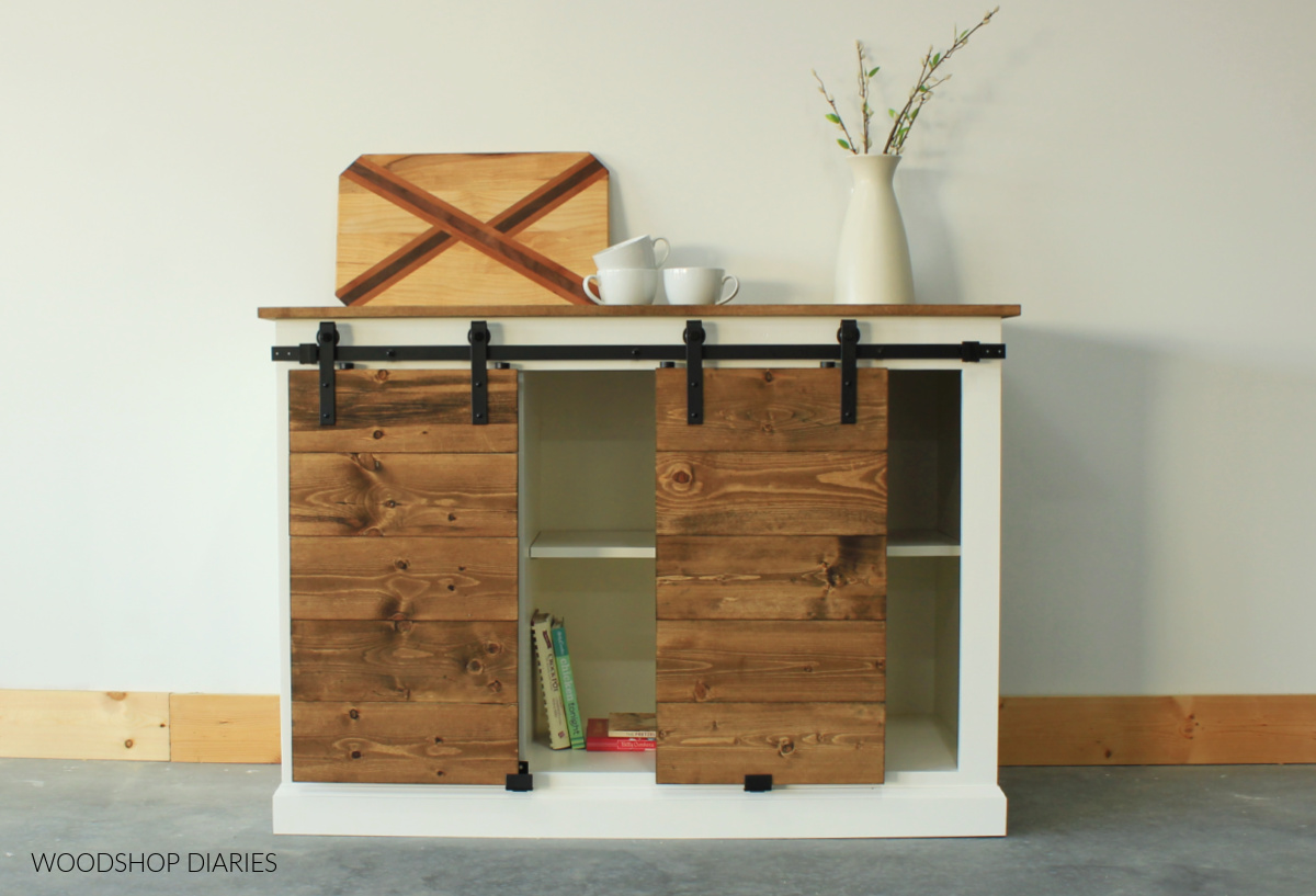 White storage cabinet with slatted wood stained sliding doors against white wall