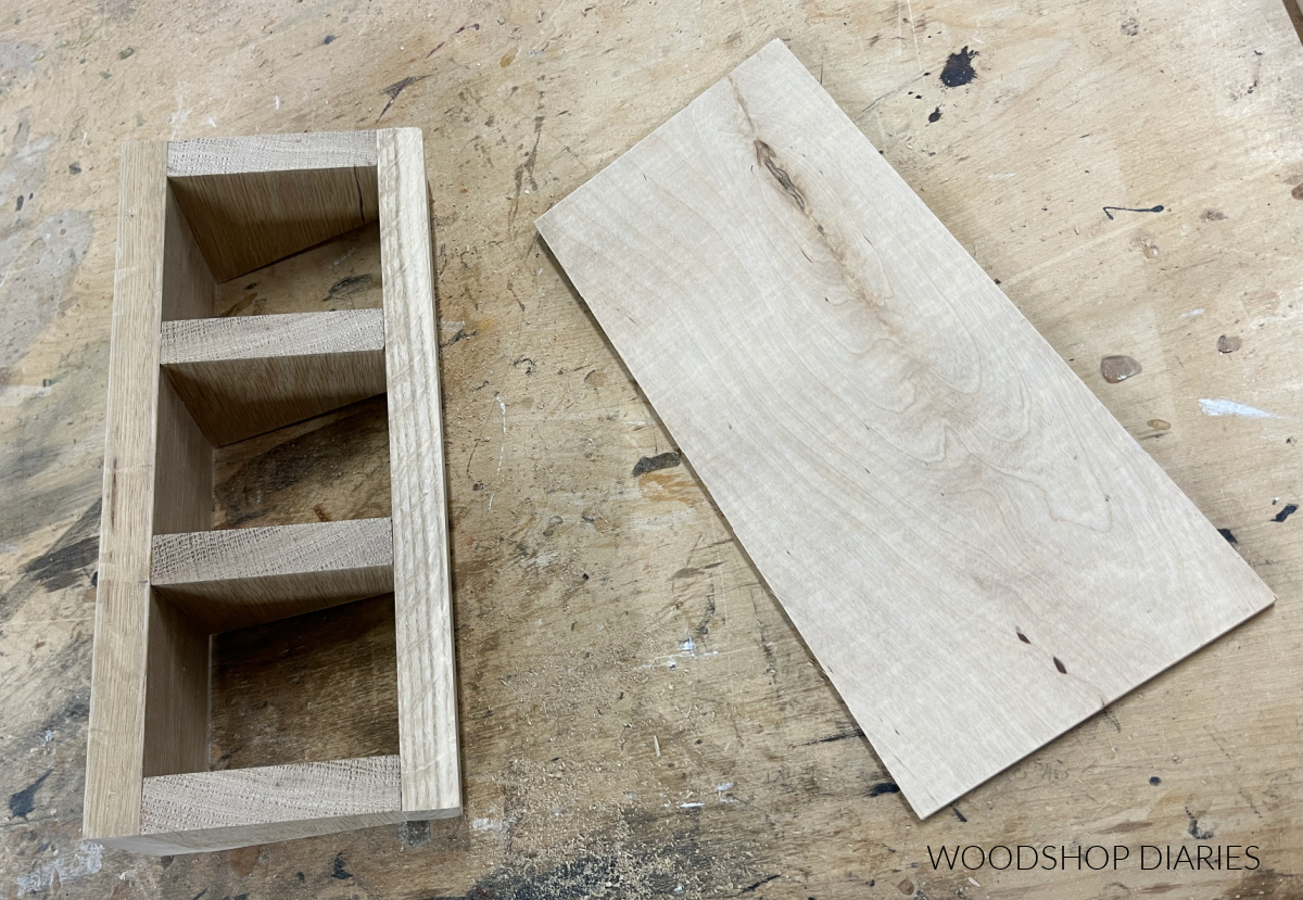 Wooden tea box frame on workbench next to ¼" plywood panel for bottom