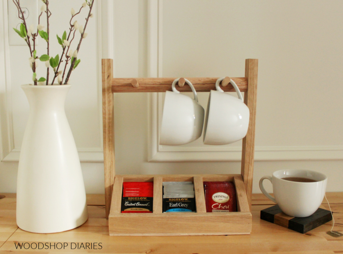 Completed oak DIY tea box storage organizer with mug holder on pegs