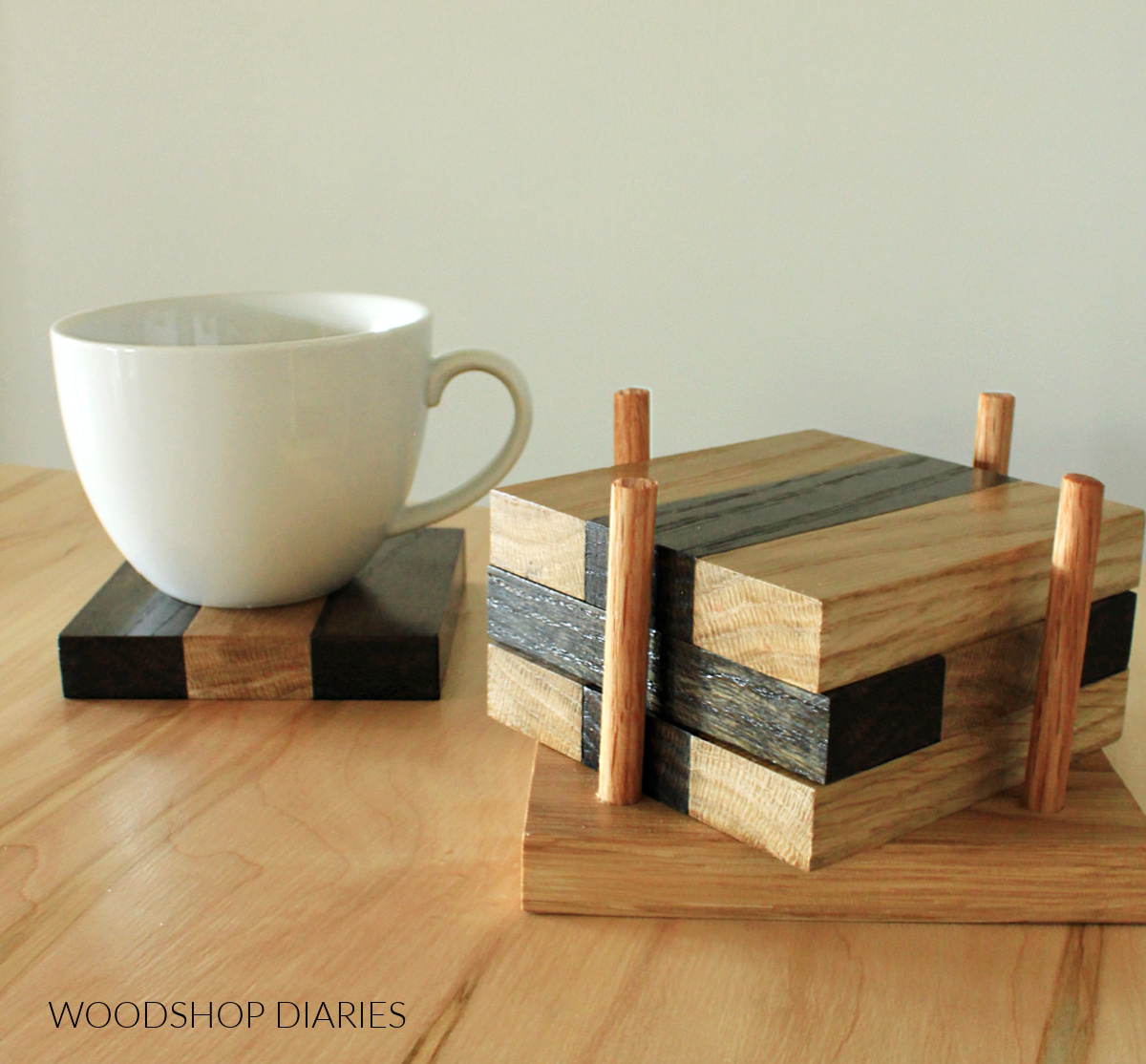 DIY two tone oak wood drink coasters stacked in stand on table with white mug