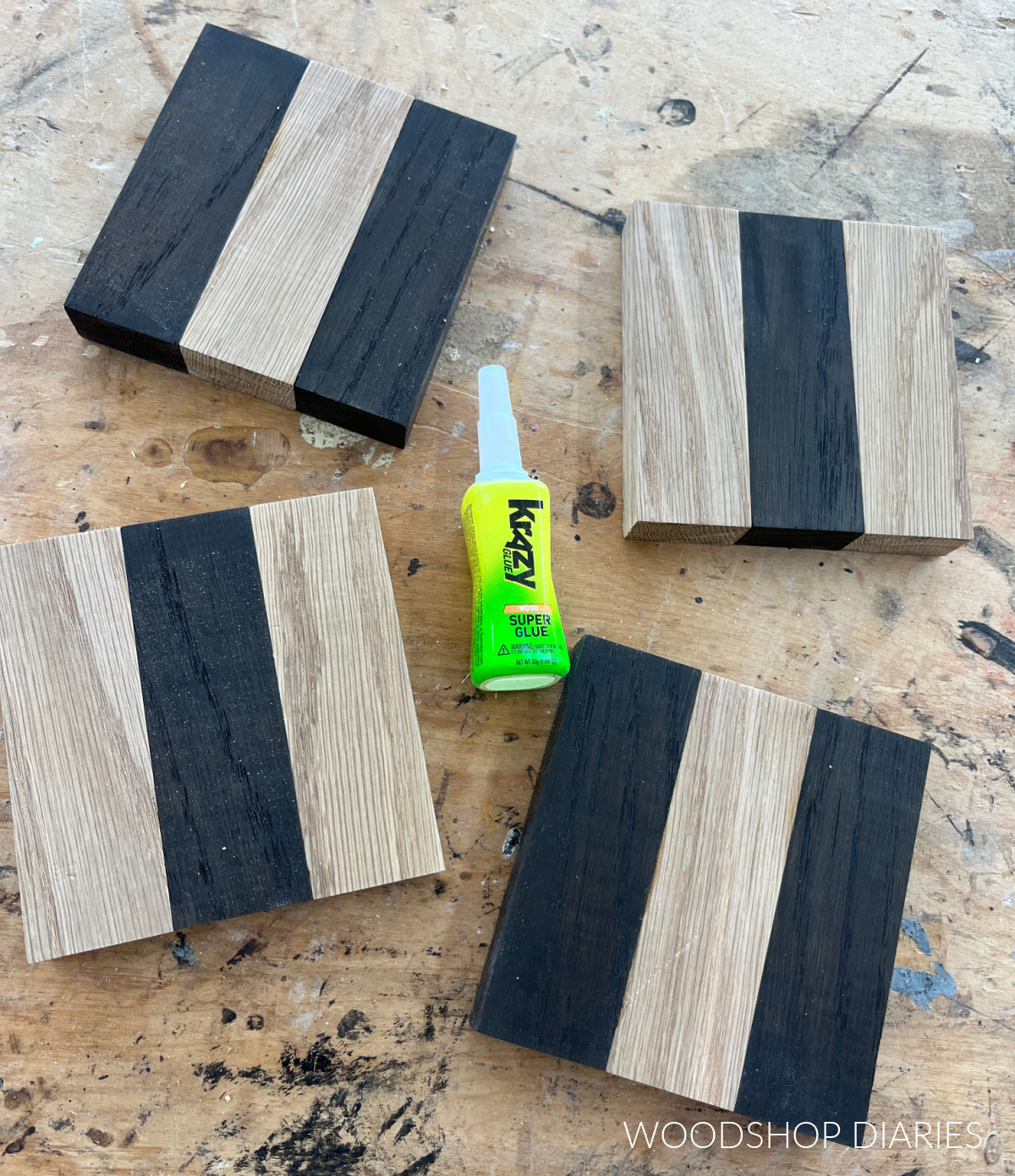 Bottle of Krazy Glue on workbench surrounded by completed wooden coasters