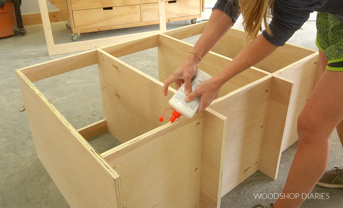 Shara Woodshop Diaries applying wood glue to front edge of cabinet
